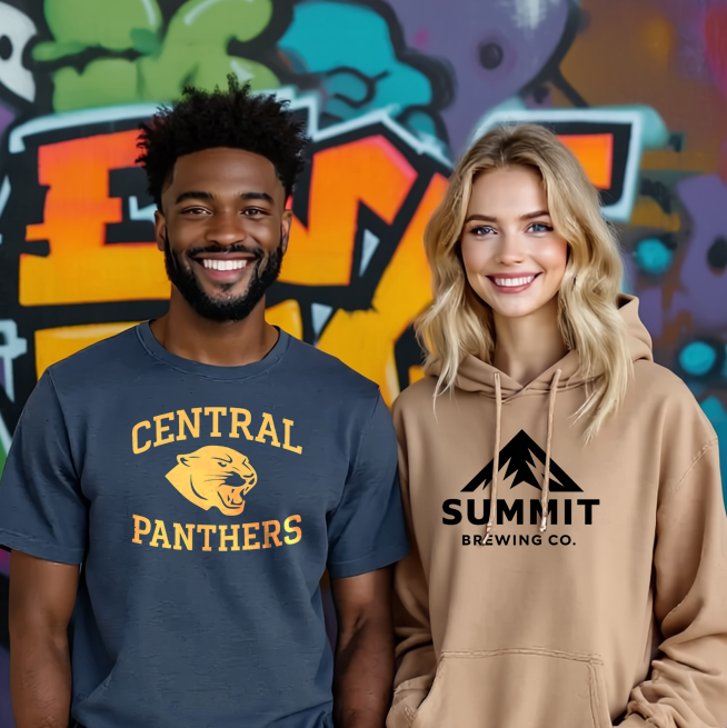 Two models wearing custom-printed T-shirt and hoodie in front of a graffiti wall; hero for ‘Create your free merch store.’